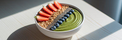 Green vegan smoothie bowl with fruit toppings