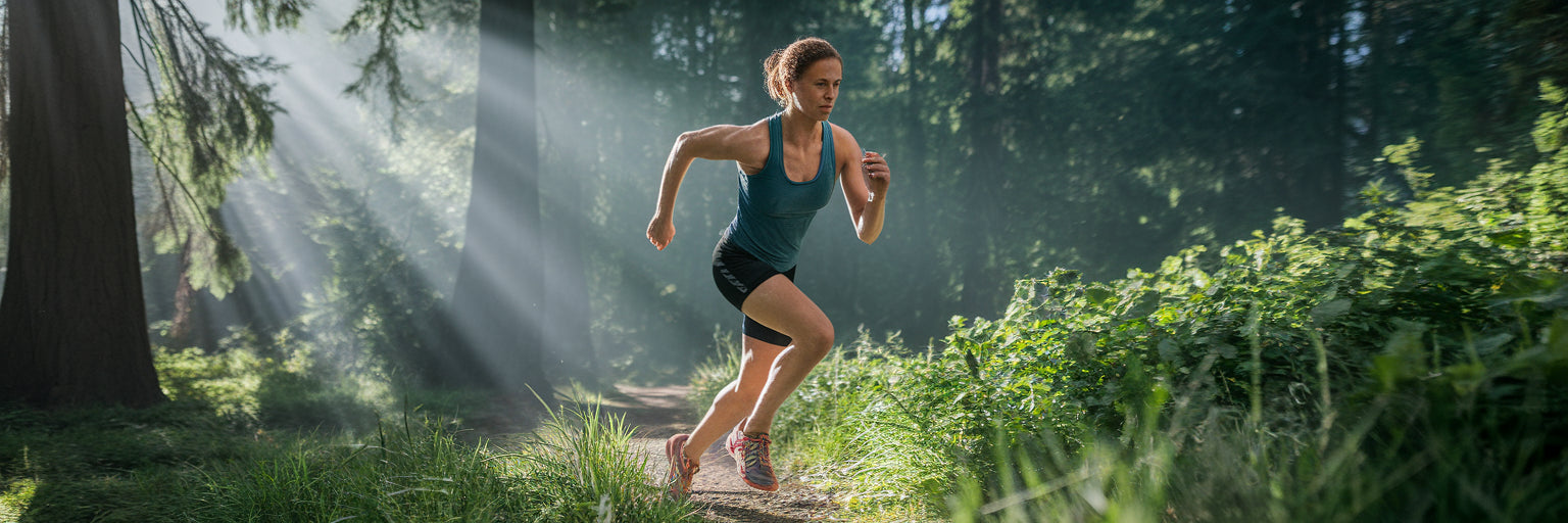 Vegan athlete running powerfully on a forest trail.