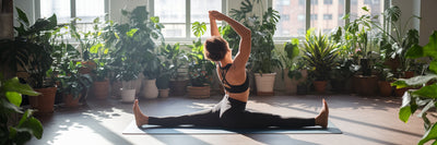 Athletic person stretching in plant-filled room.