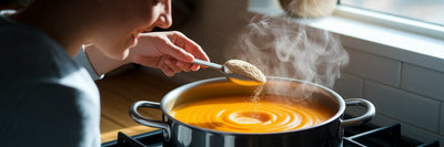 Person adding protein powder to soup.