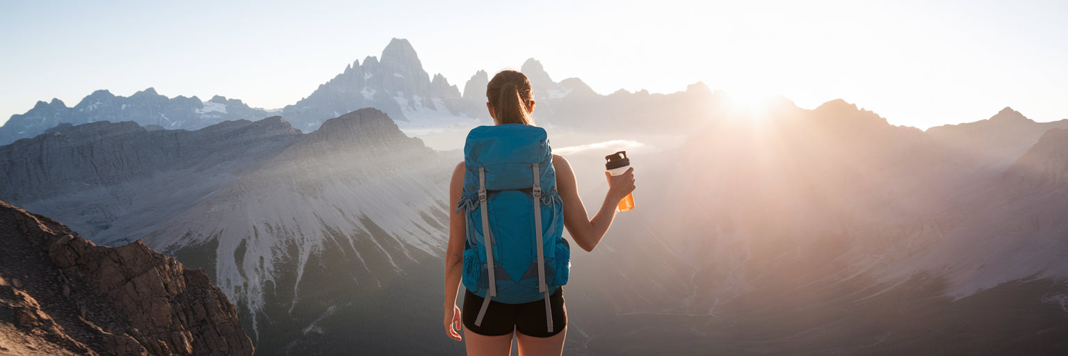 Hiker with protein shake on mountain summit.
