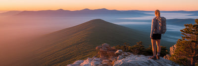 Hiker enjoying a scenic mountain sunrise.