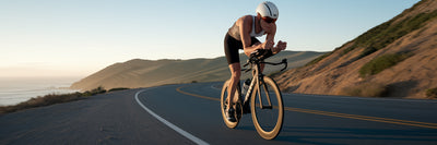 Triathlete cycling on a coastal highway.