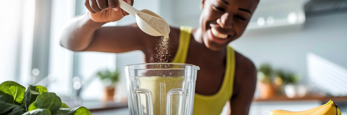 Person scooping vegan protein powder into a blender.