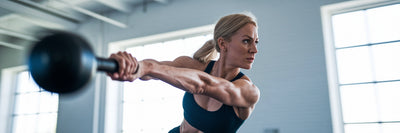 Woman performing a kettlebell swing during HIIT.