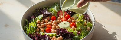 Drizzling protein dressing on a salad.